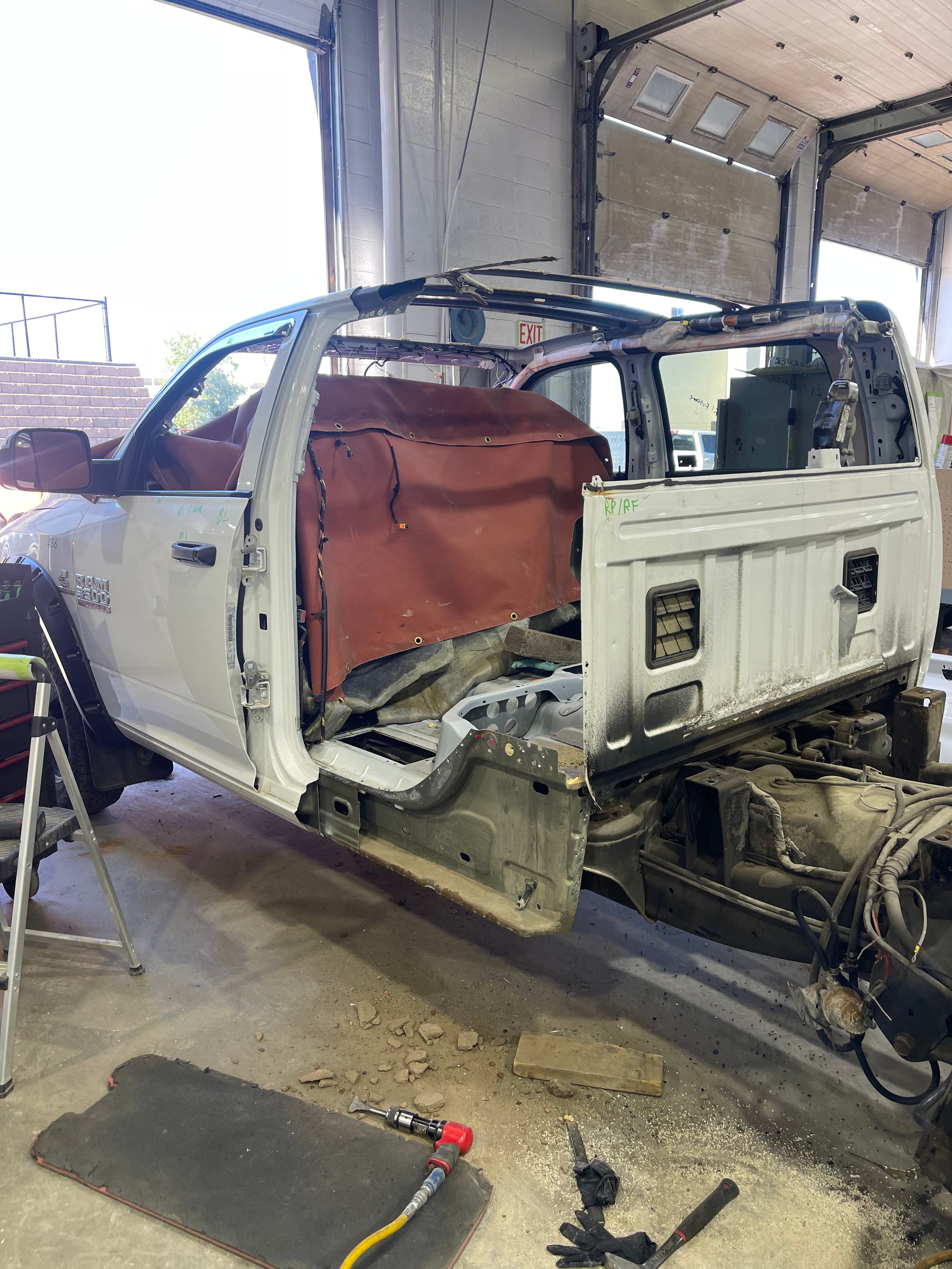 Partially disassembled white vehicle undergoing collision repair in the MACART workshop